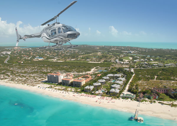 A photograph of a TCI Helicopters helicopter flying over the Turks and Caicos Islands